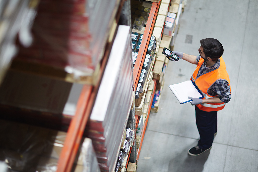 AdobeStock_151809562 Worker with scanner making review of goods in warehouse